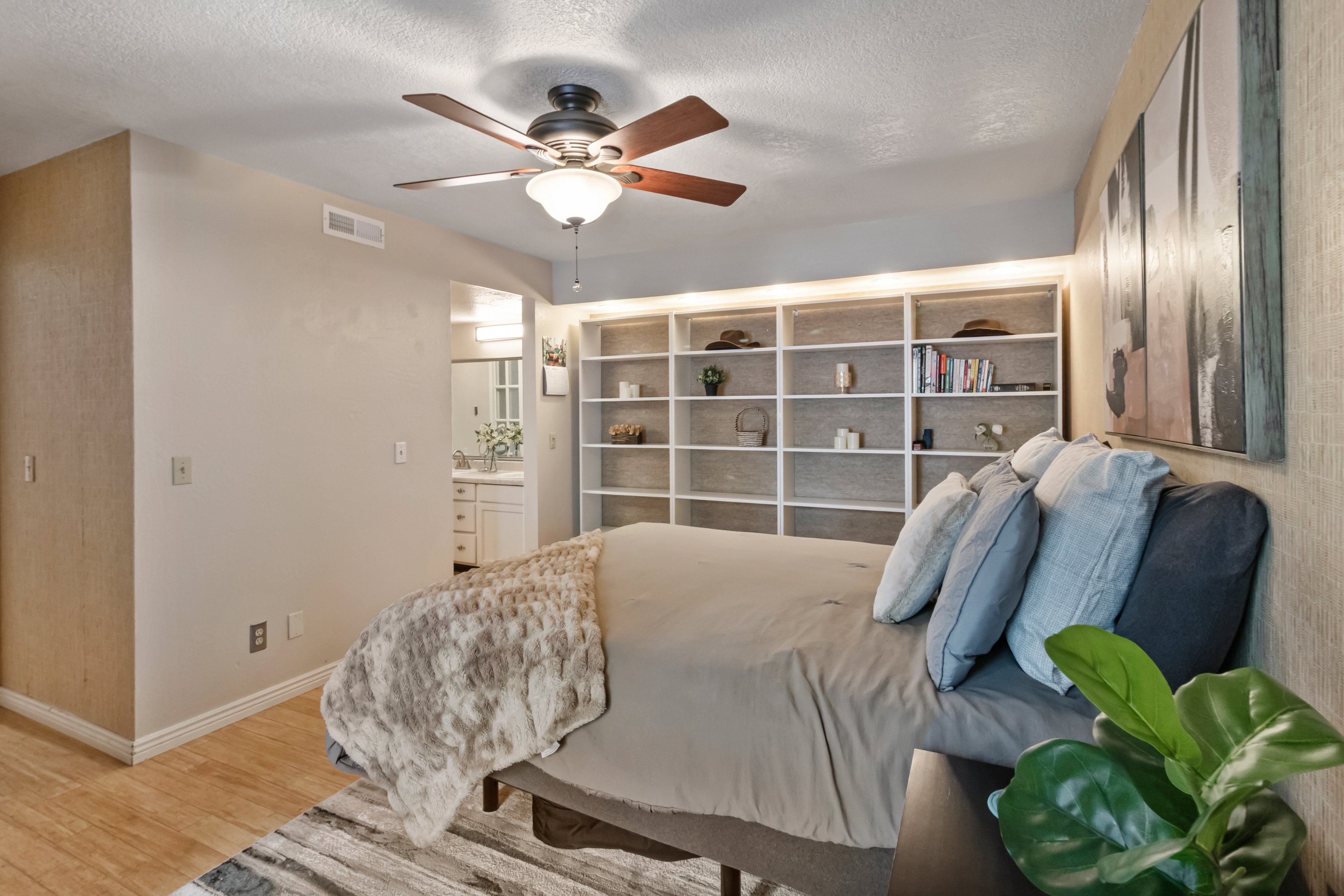 Bedroom featuring wood finished floors, a textured ceiling, ceiling fan, and ensuite bathroom