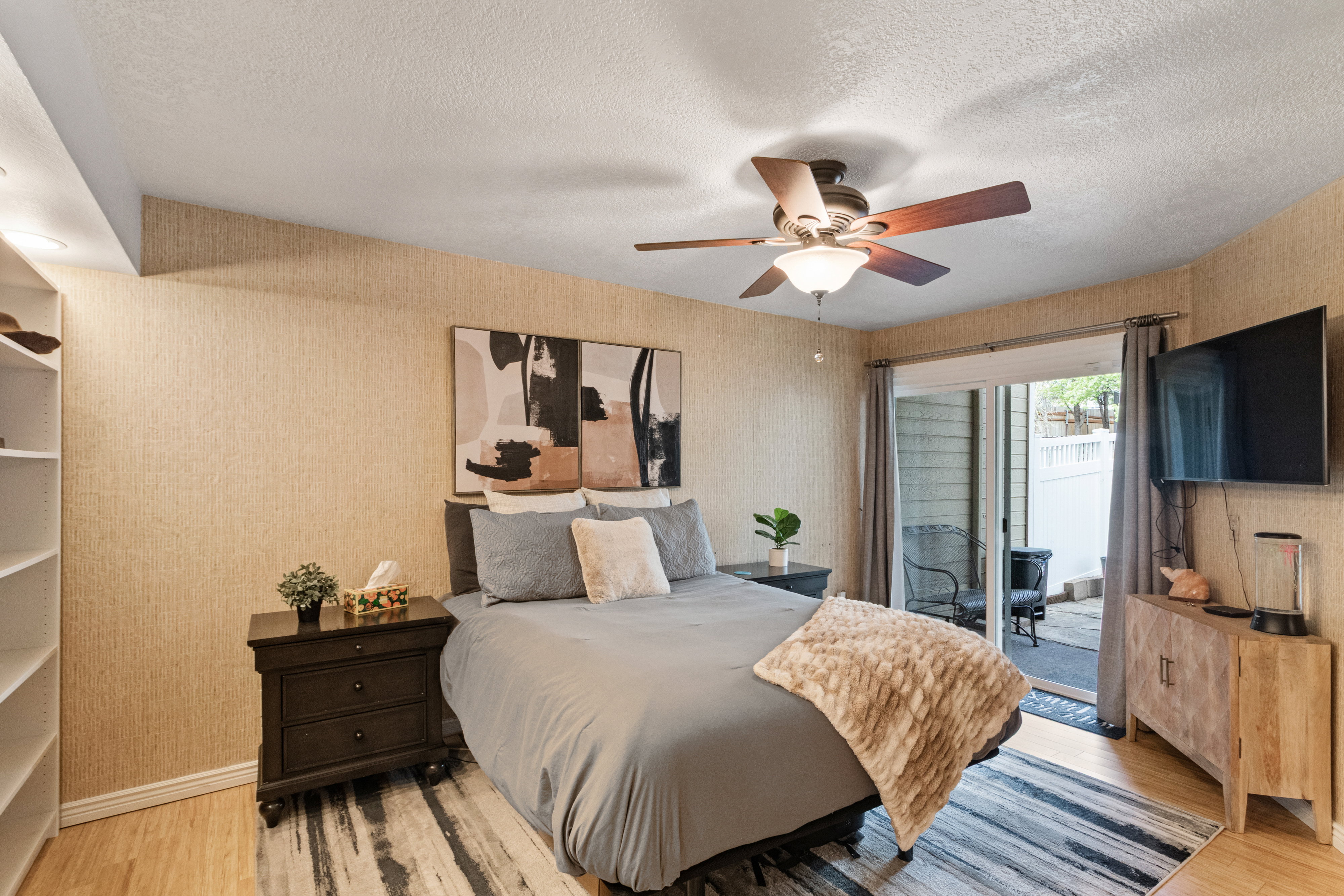 Bedroom with wood finished floors, access to outside, a ceiling fan, a textured ceiling, and wallpapered walls