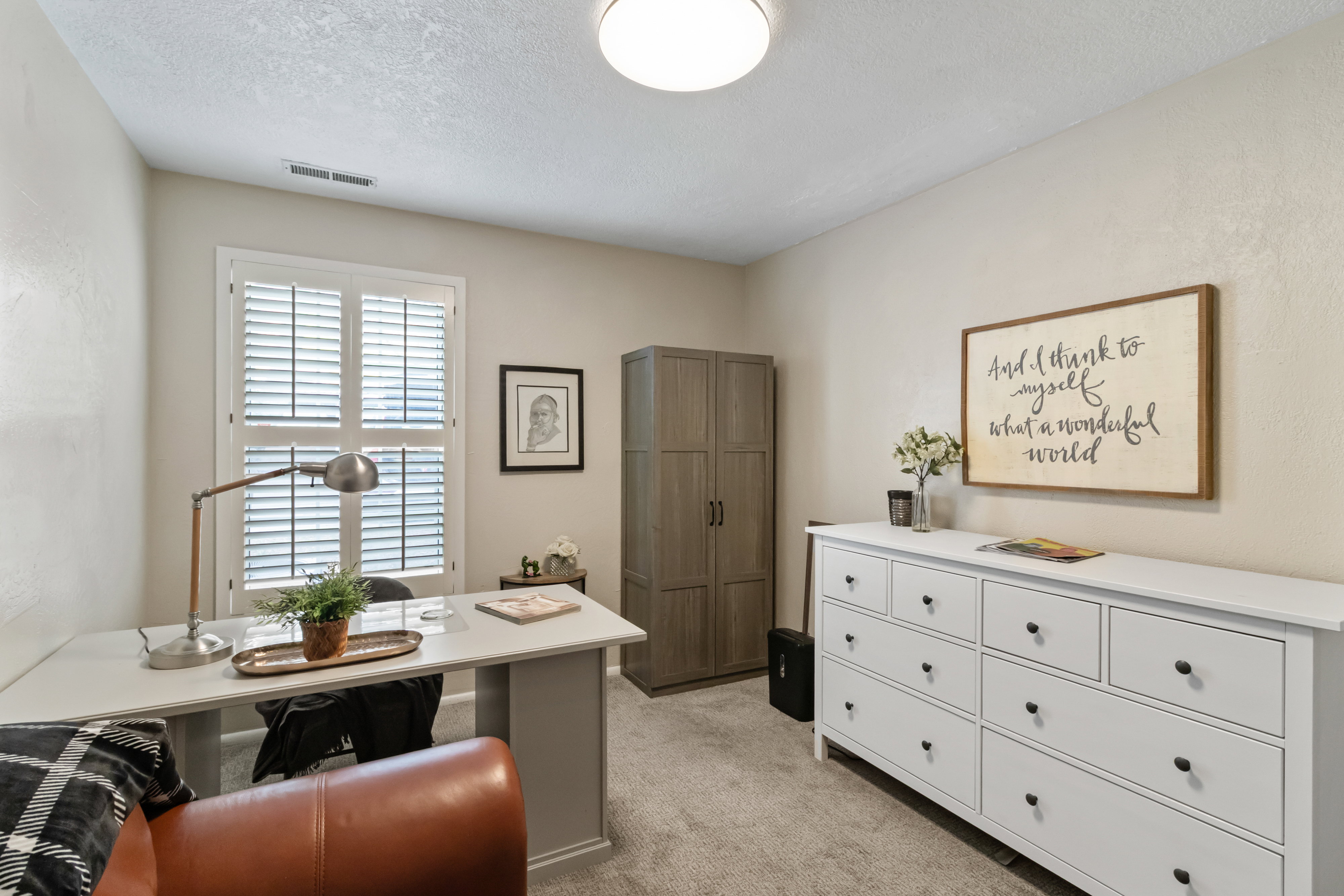 Home office with light colored carpet and a textured ceiling