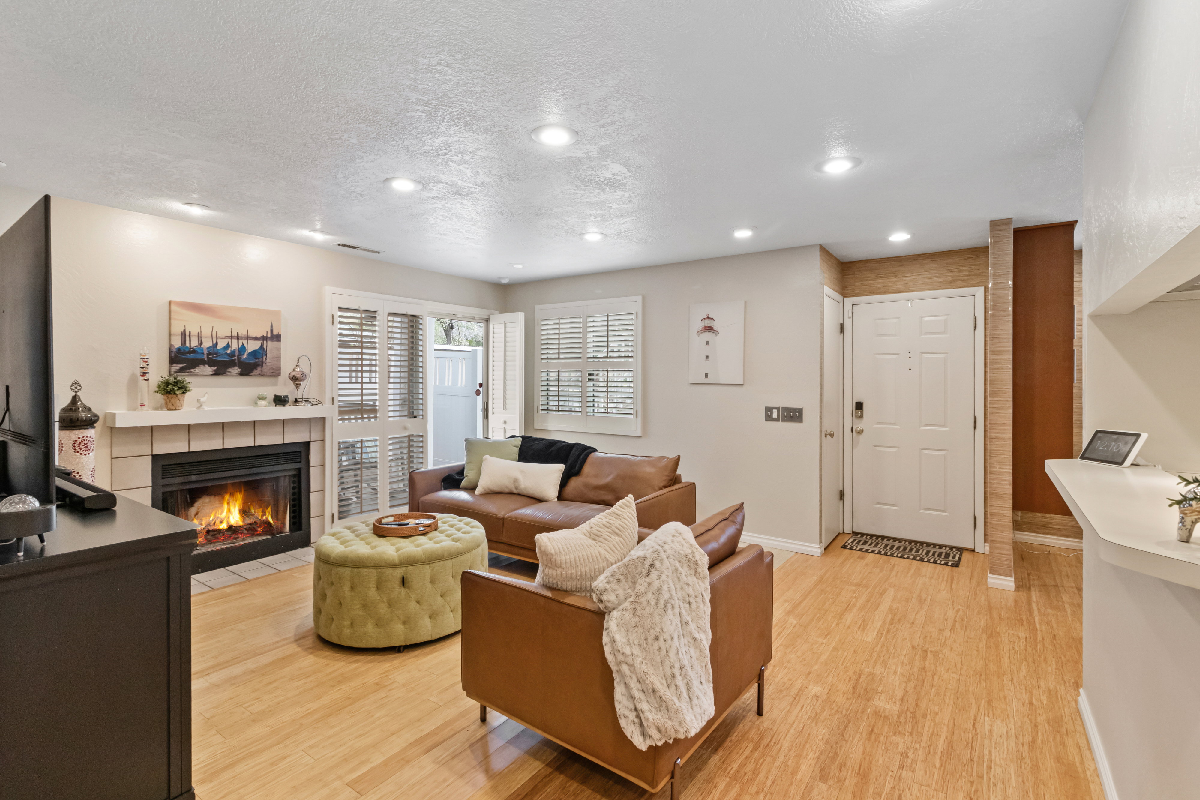 Living room featuring light wood-style floors, a tile fireplace, a textured ceiling, and recessed lighting