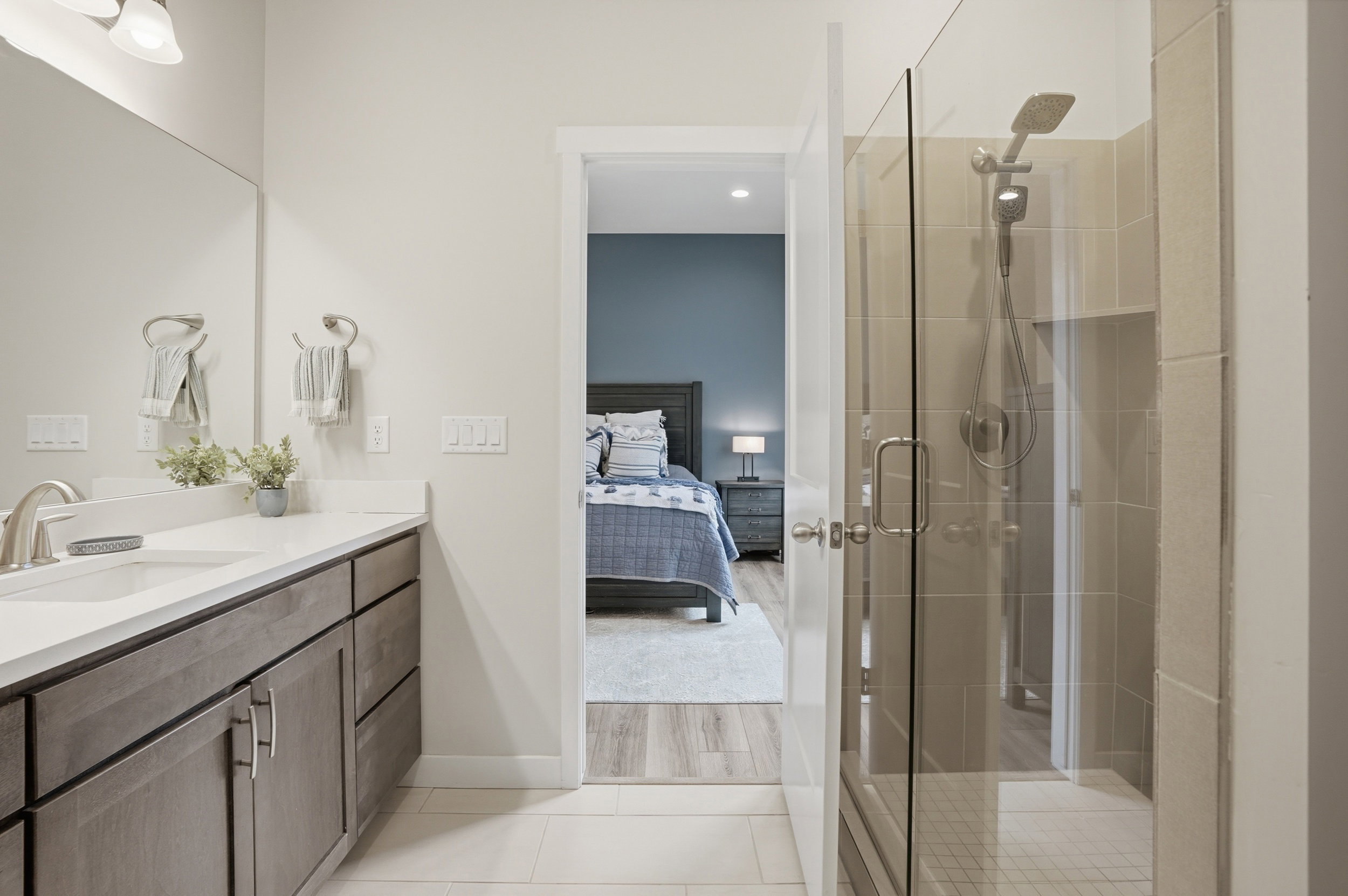 Full bath with connected bathroom, a stall shower, vanity, and light tile patterned flooring