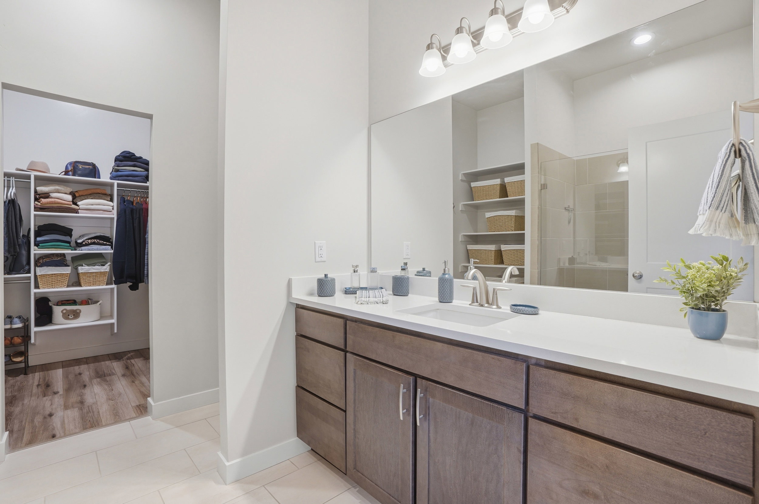 Full bath featuring vanity, light tile patterned floors, a spacious closet, and a stall shower