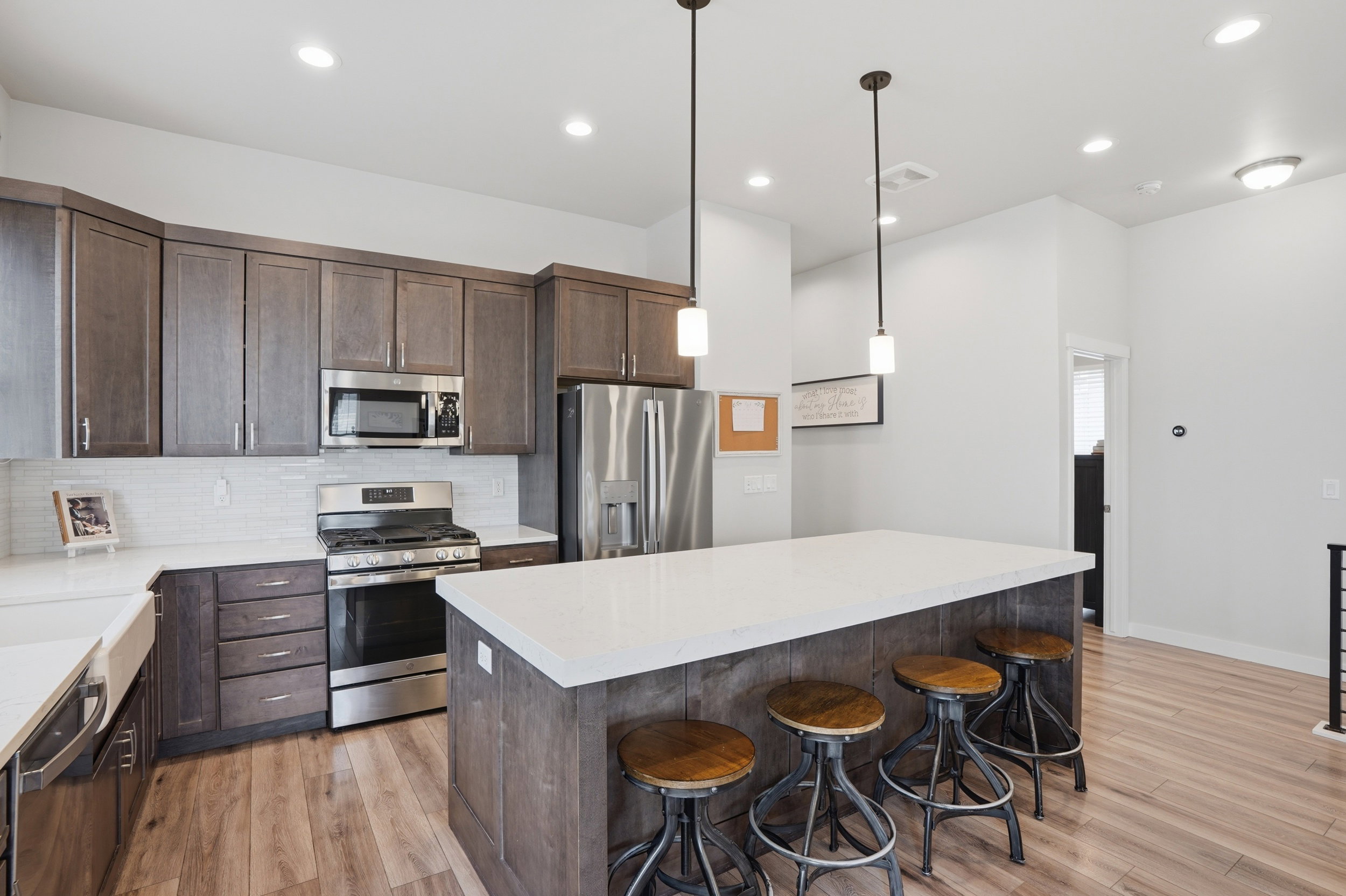 Kitchen with dark wood finish cabinets, stainless steel appliances, decorative backsplash, a center island, and light wood-type flooring