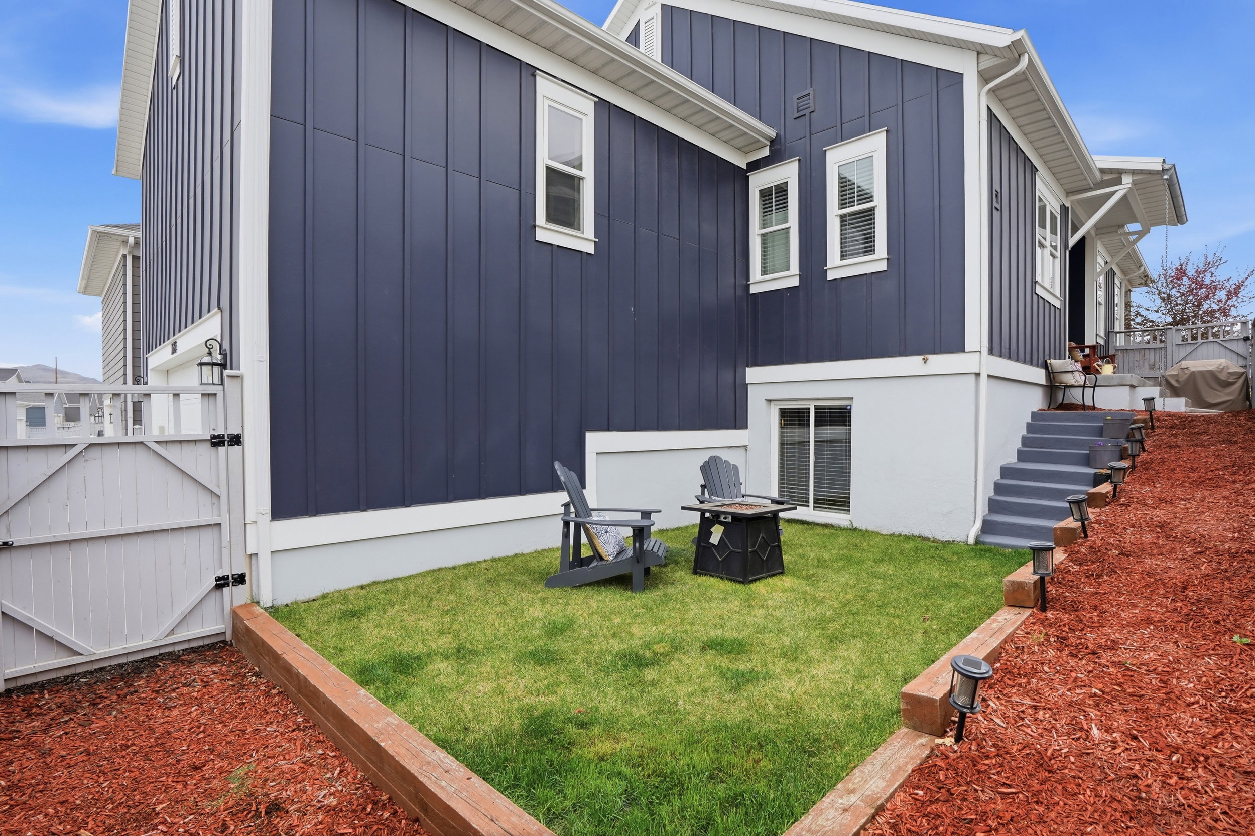 Rear view of house with a gate, an outdoor fire pit, and board and batten siding