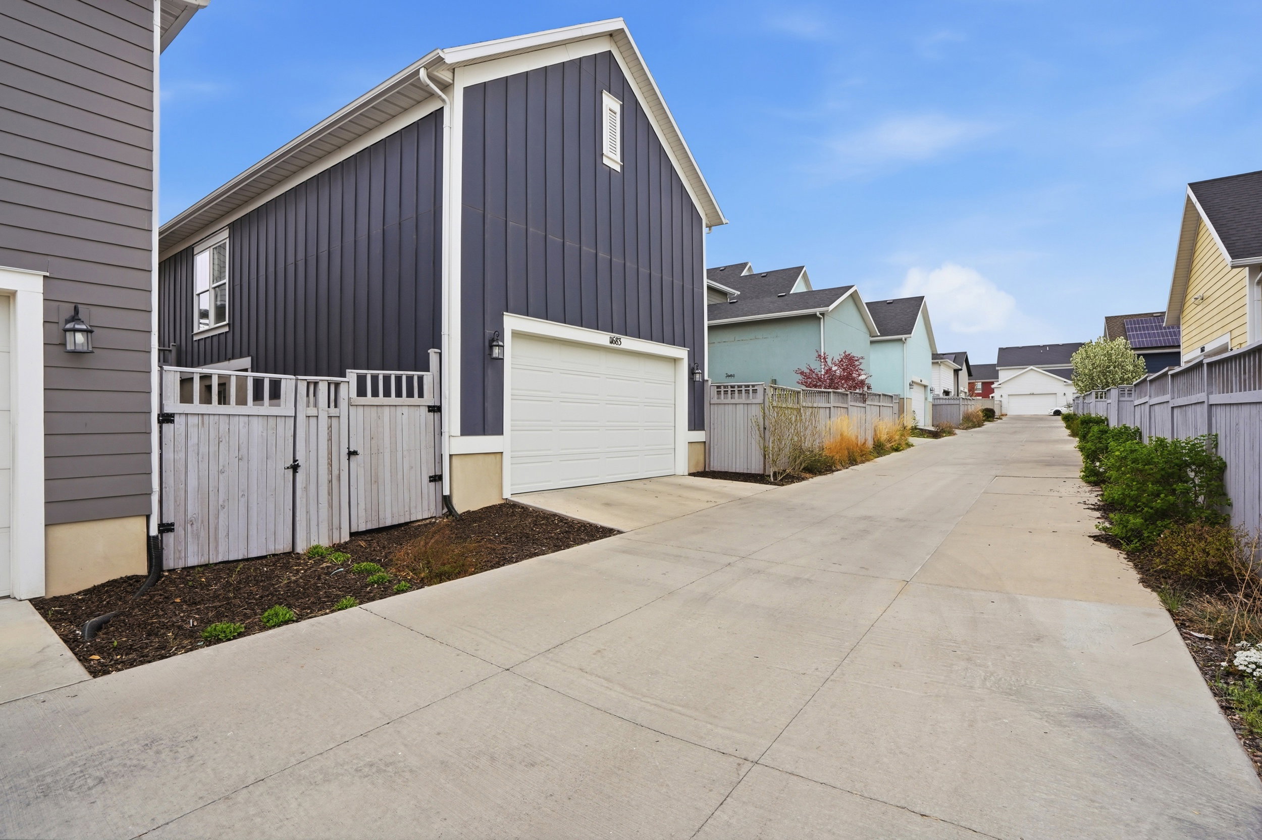 View of home's exterior with a gate, board and batten siding, concrete driveway, and a residential view