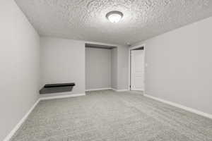 Empty room with a textured ceiling and light colored carpet