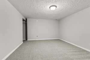 Unfurnished room with light carpet and a textured ceiling