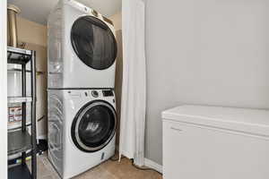 Laundry area with light tile patterned floors and stacked washer / dryer