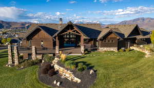 View of front of home with a mountain view, stone siding, a front yard, and board and batten siding