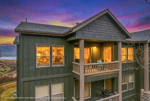 Rear view of house with board and batten siding, a shingled roof, and a balcony