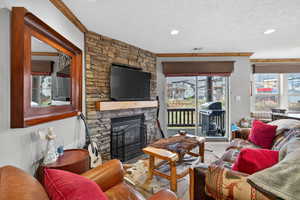 Living room featuring a fireplace, crown molding, and a textured ceiling