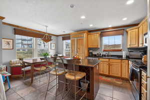 Kitchen with stone tile flooring, a kitchen bar, stainless steel appliances, a kitchen island, and crown molding