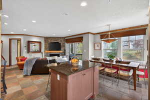 Kitchen with stone tile floors, dark stone countertops, a kitchen bar, a textured ceiling, and a kitchen island
