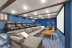 Home theater with beamed ceiling and carpet flooring