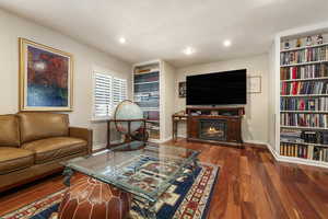 Living area featuring dark wood-type flooring and a glass covered fireplace