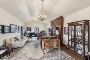 Living area with vaulted ceiling, hanging lights, and wood finished floors