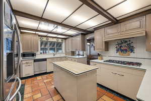 Kitchen with stainless steel appliances, tasteful backsplash, a center island, and cream cabinetry