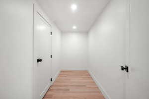 Hallway with light wood-style flooring and recessed lighting