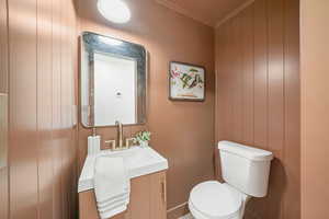 Bathroom with vanity, ornamental molding, and wooden walls