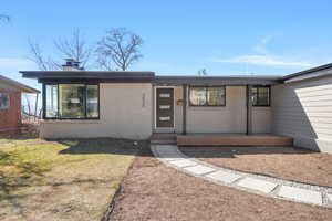 View of front of home with a chimney, brick siding, and a front lawn