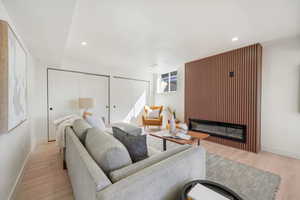 Living area featuring a glass covered fireplace, light wood-style flooring, and recessed lighting