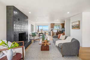 Living area featuring light wood-type flooring, a tiled fireplace, and recessed lighting