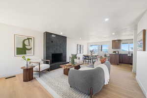 Living room with light wood-type flooring, a fireplace, and recessed lighting