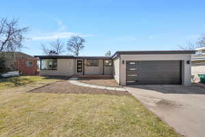 View of front of property featuring a front yard, concrete driveway, and a chimney