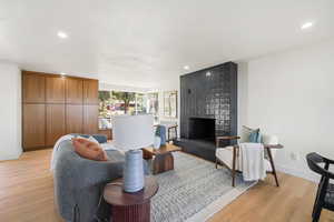 Living area with a fireplace, light wood-style flooring, and recessed lighting