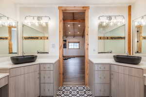 Bathroom featuring two vanities, beamed ceiling, recessed lighting, and light wood-style floors