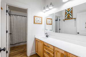 Bathroom featuring vanity, curtained shower, and dark wood-style floors
