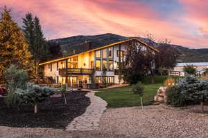 Back of house featuring a balcony, a patio, a chimney, stucco siding, and a mountain view