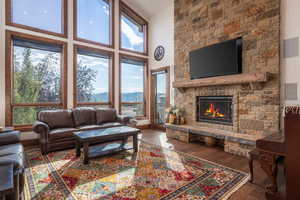 Living area featuring a high ceiling, hardwood / wood-style floors, and a stone fireplace