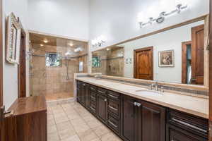 Bathroom with double vanity, a shower stall, and light tile patterned floors