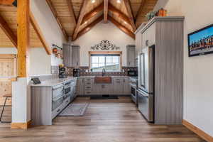 Kitchen with gray cabinetry, high quality appliances, a high wood beamed ceiling, backsplash, and dark wood finished floors