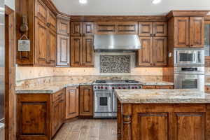 Kitchen with stainless steel appliances, light wood-style floors, wood finish cabinetry, decorative backsplash, and recessed lighting