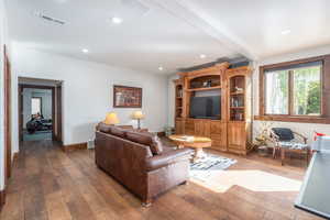 Living area featuring wood-type flooring, recessed lighting, and beam ceiling