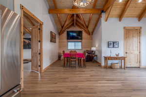 Dining area featuring a high wooden beamed ceiling, wood finished floors, and a chandelier
