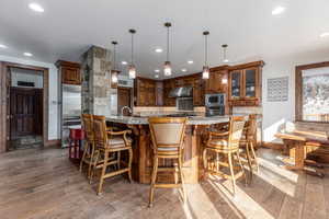 Kitchen with dark wood-type flooring, a breakfast bar, stainless steel appliances, wood finish cabinets, and pendant lighting
