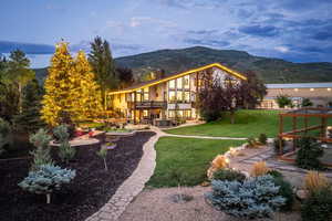 Back of house with a patio area, a balcony, a chimney, a mountain view, and stucco siding