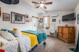 Carpeted bedroom featuring lofted ceiling with beams, a wall mounted mini split, and a ceiling fan