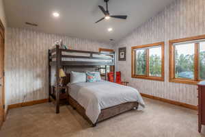 Bedroom with vaulted ceiling, recessed lighting, light colored carpet, a ceiling fan, and wooden walls