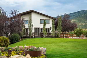 Rear view of property with a yard, a wooden deck, and stucco siding