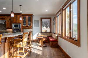 Kitchen with breakfast area, wood finish cabinets, stainless steel appliances, dark wood-style floors, and glass fronted cabinets