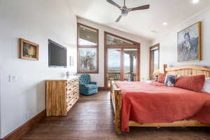 Bedroom featuring dark wood-type flooring, access to exterior, ceiling fan, and lofted ceiling