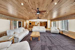 Carpeted living area featuring ceiling fan, wood walls, a wainscoted wall, recessed lighting, and wooden ceiling