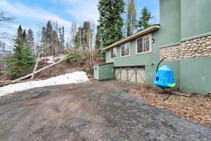 View of side of property with an attached garage, stucco siding, and asphalt driveway