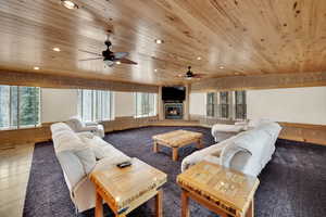 Living room featuring a glass covered fireplace, recessed lighting, carpet flooring, wood ceiling, and a ceiling fan