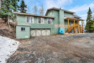 View of front facade with an attached garage, driveway, a metal roof, stucco siding, and stone siding