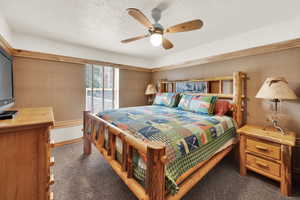Bedroom featuring dark colored carpet, ceiling fan, and a textured ceiling
